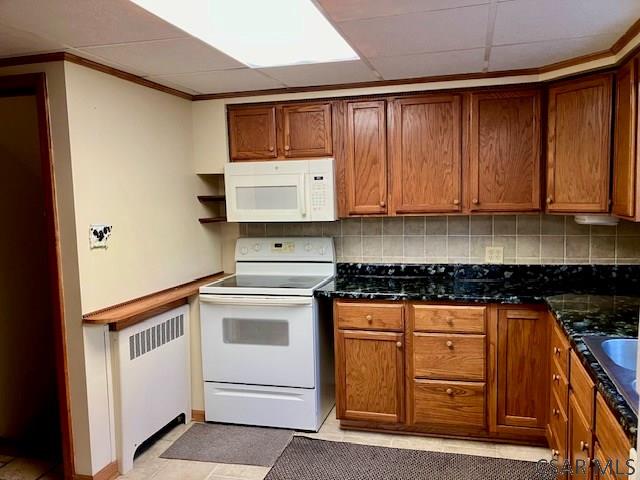 kitchen featuring tasteful backsplash, brown cabinets, white appliances, and radiator