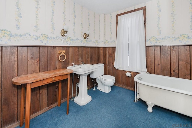 bathroom featuring toilet, a bathtub, and wood walls