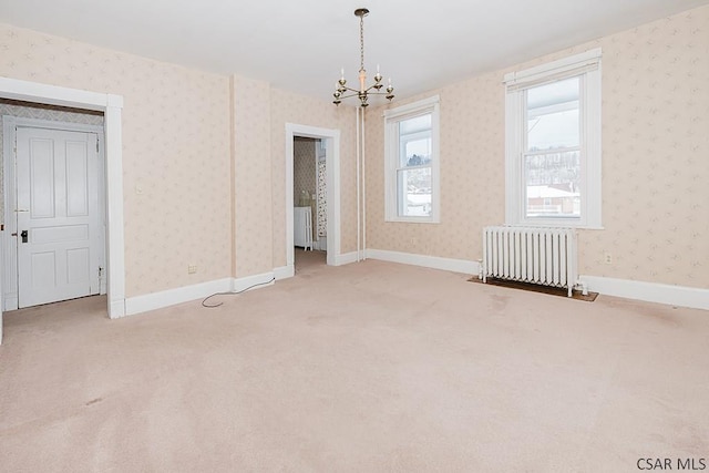 carpeted spare room featuring radiator heating unit and a chandelier