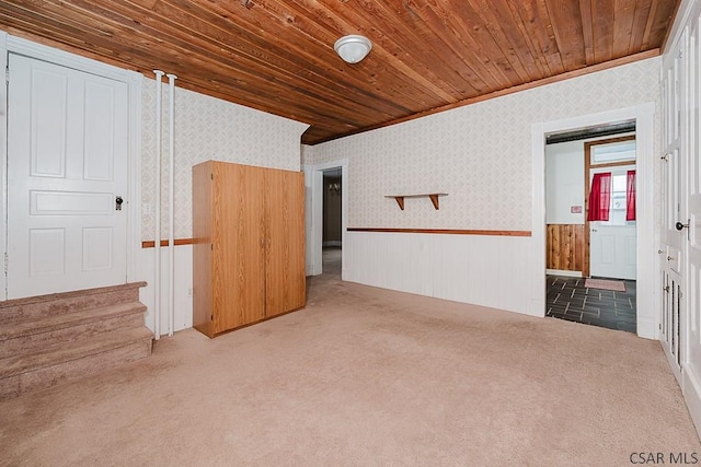 carpeted empty room featuring crown molding and wooden ceiling