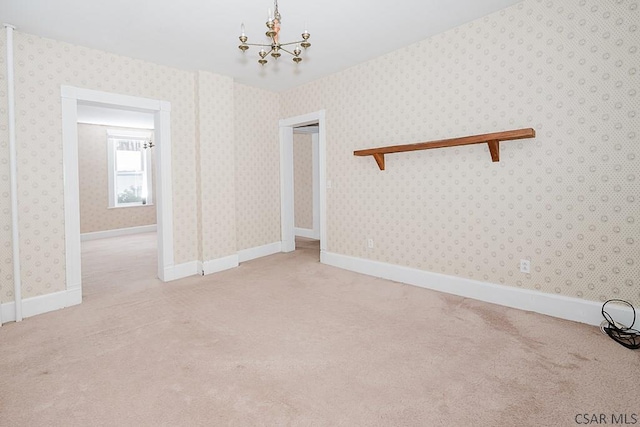 empty room featuring light colored carpet and a notable chandelier