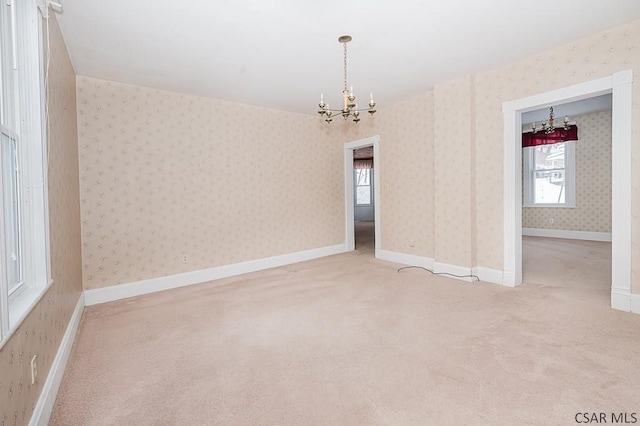 carpeted empty room featuring an inviting chandelier