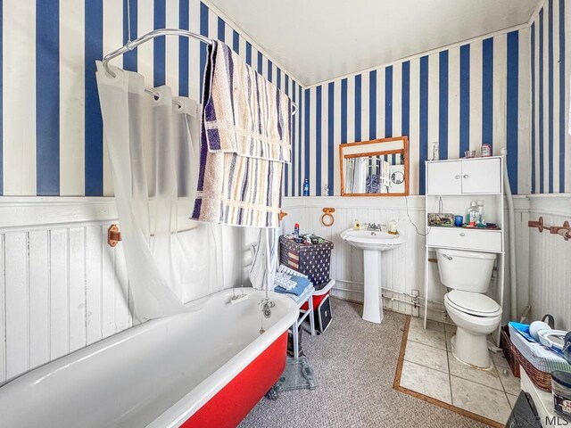 bathroom featuring tile patterned floors, toilet, sink, and a tub