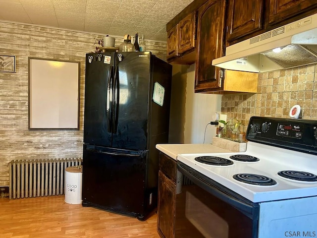 kitchen with range with electric stovetop, radiator heating unit, wooden walls, dark brown cabinetry, and black fridge