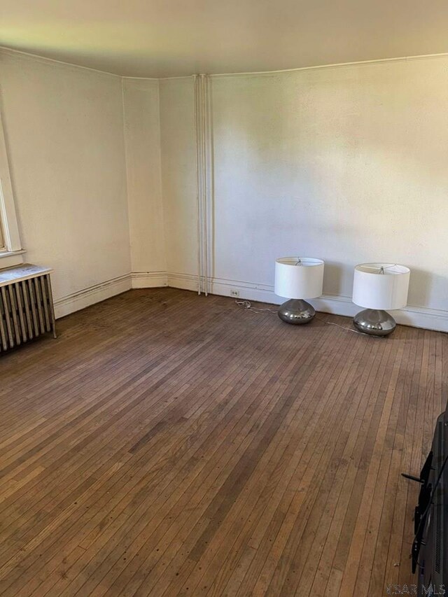 spare room featuring dark wood-type flooring and radiator heating unit