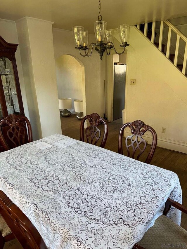 dining space featuring crown molding, hardwood / wood-style floors, and a notable chandelier