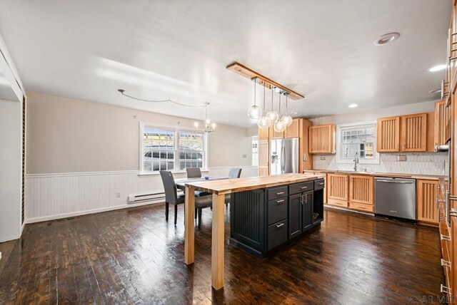 kitchen with pendant lighting, sink, appliances with stainless steel finishes, a center island, and dark hardwood / wood-style flooring