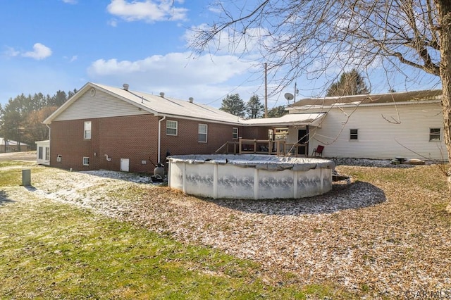 back of house featuring crawl space, a covered pool, and brick siding