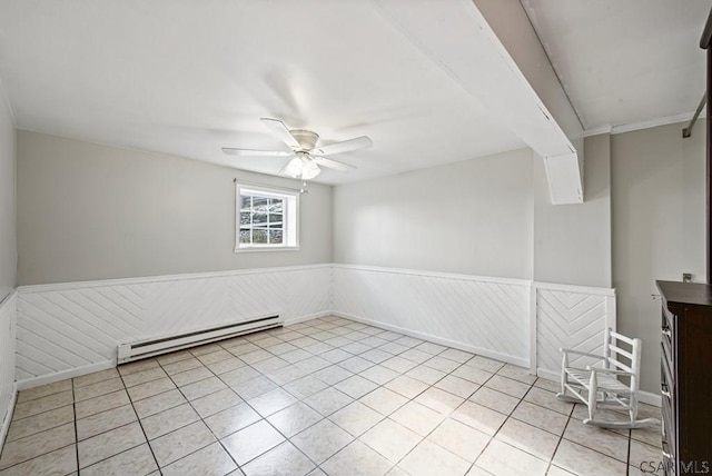 unfurnished room with light tile patterned floors, a baseboard radiator, a ceiling fan, and wainscoting