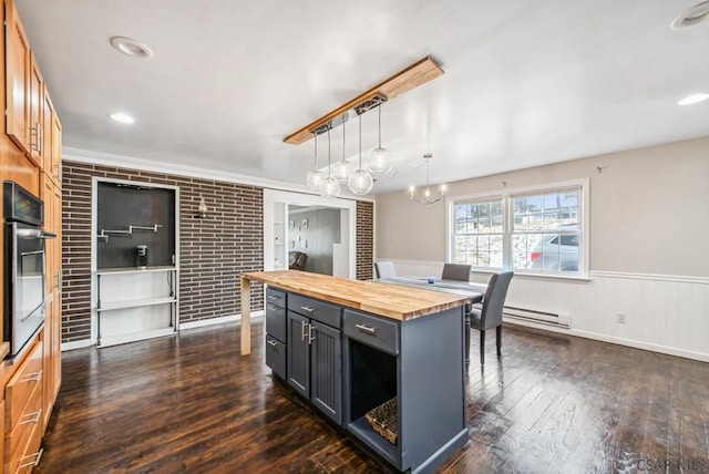 kitchen featuring butcher block countertops, stainless steel oven, a center island, hanging light fixtures, and a baseboard radiator