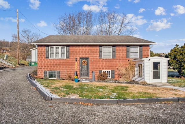 split foyer home featuring a front lawn and brick siding