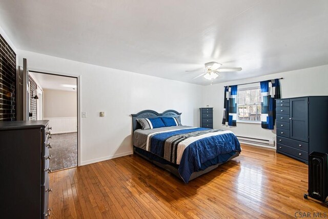 bedroom featuring hardwood / wood-style flooring, a baseboard radiator, and ceiling fan