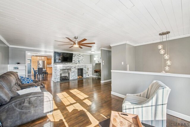 living room featuring dark wood-type flooring, wood ceiling, ornamental molding, ceiling fan, and a fireplace