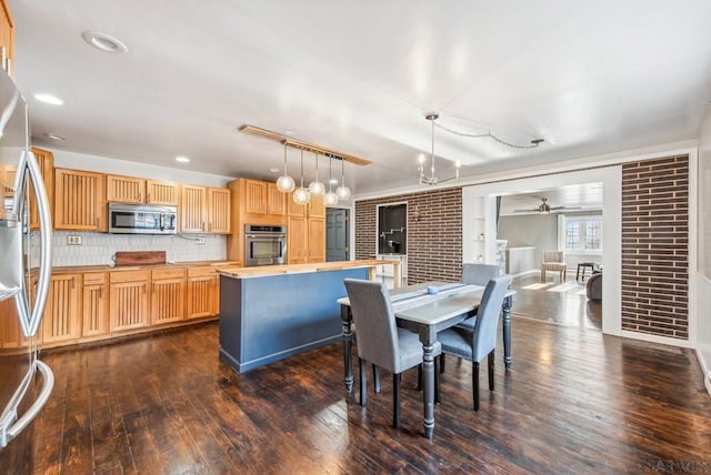 dining area featuring dark hardwood / wood-style flooring, ceiling fan with notable chandelier, and brick wall