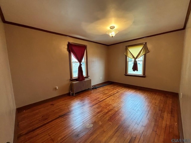 empty room with hardwood / wood-style flooring, ornamental molding, and radiator heating unit