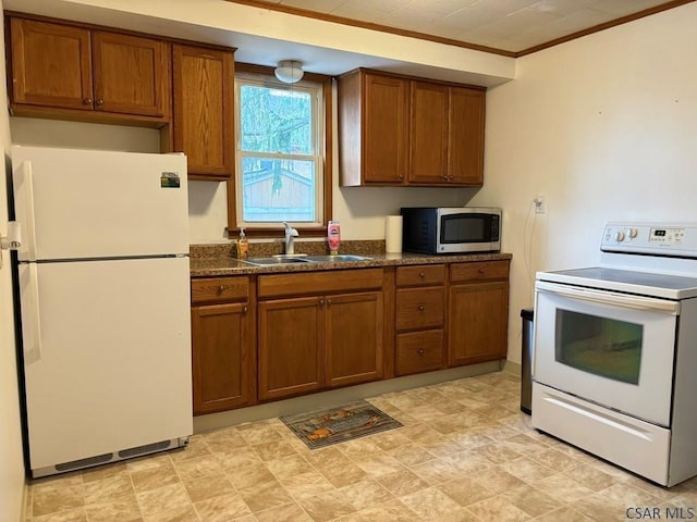 kitchen with white appliances, ornamental molding, sink, and dark stone countertops