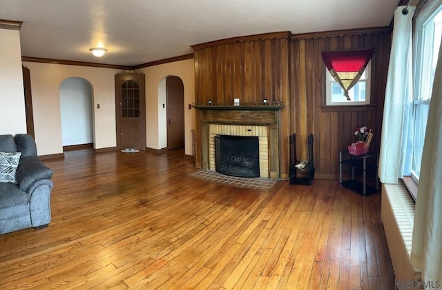 living room featuring hardwood / wood-style floors, crown molding, a brick fireplace, and a wealth of natural light