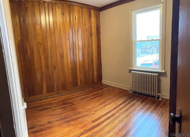 spare room with hardwood / wood-style flooring, crown molding, and radiator