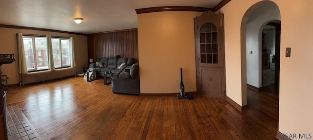 unfurnished living room featuring dark hardwood / wood-style flooring, radiator heating unit, and ornamental molding