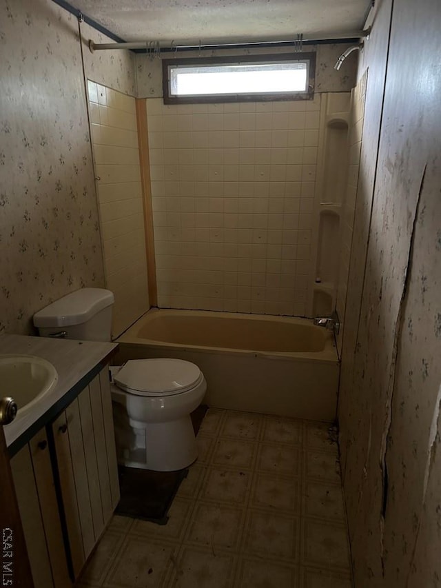 full bathroom with tiled shower / bath, vanity, toilet, and a textured ceiling