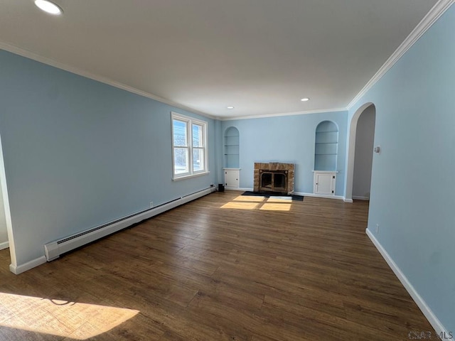 unfurnished living room featuring built in shelves, baseboard heating, ornamental molding, dark hardwood / wood-style floors, and a fireplace