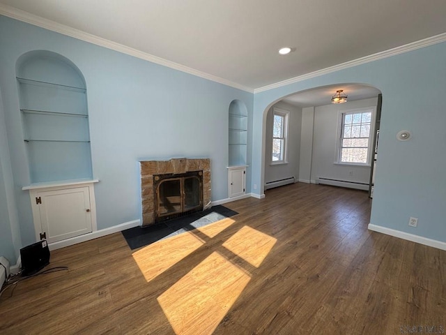 unfurnished living room with a stone fireplace, built in features, dark hardwood / wood-style floors, and baseboard heating