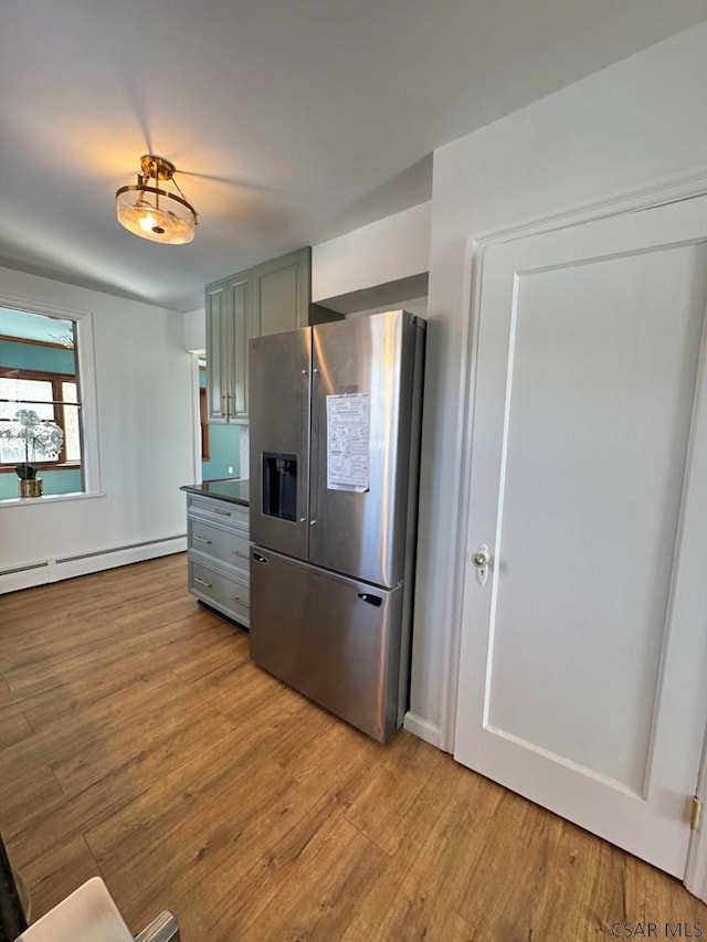 kitchen with a baseboard heating unit, stainless steel fridge, and light wood-type flooring