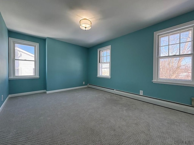 carpeted empty room featuring a baseboard heating unit and a wealth of natural light