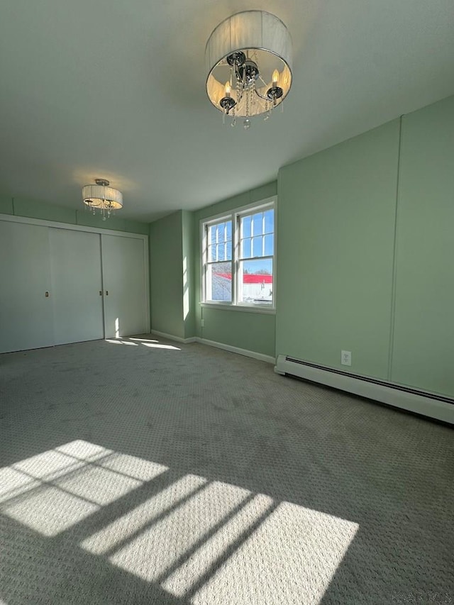 empty room featuring baseboard heating and carpet flooring