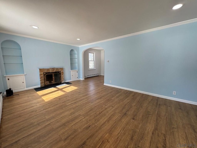 unfurnished living room with crown molding, baseboard heating, hardwood / wood-style floors, a fireplace, and built in shelves