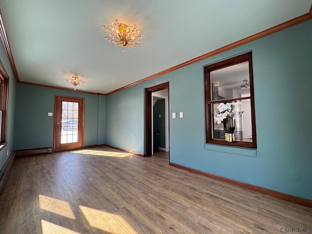 empty room featuring crown molding, baseboard heating, and light hardwood / wood-style flooring