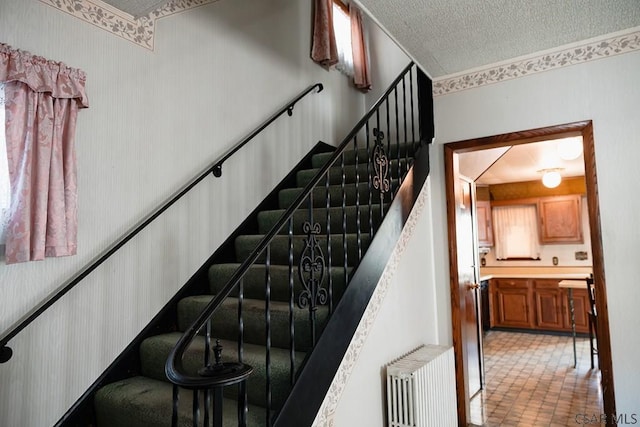 staircase with radiator and a textured ceiling