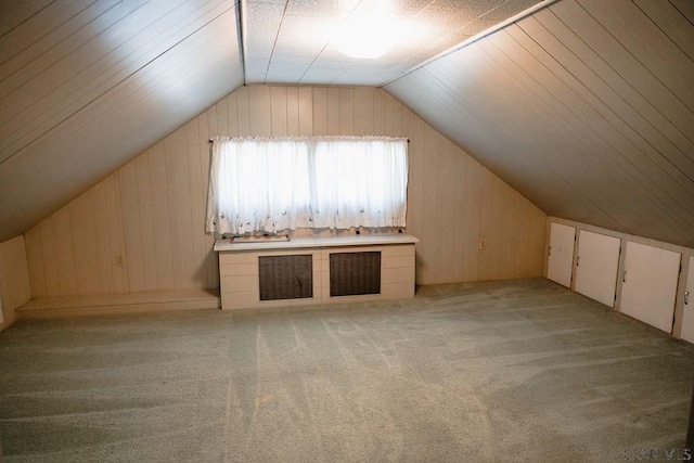 additional living space featuring lofted ceiling, wooden walls, and light colored carpet