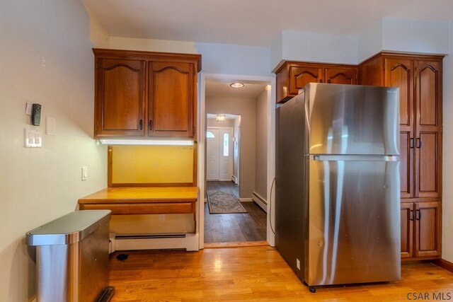 kitchen featuring light wood-type flooring, stainless steel fridge, and baseboard heating