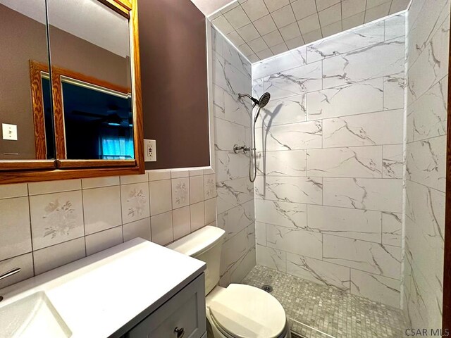 bathroom featuring tiled shower, toilet, tasteful backsplash, tile walls, and vanity