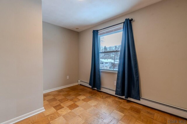 unfurnished room with a baseboard radiator and light parquet flooring