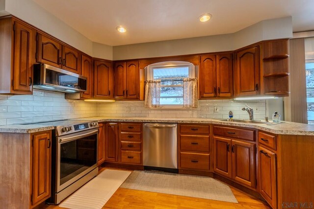 kitchen with tasteful backsplash, stainless steel appliances, and light hardwood / wood-style floors