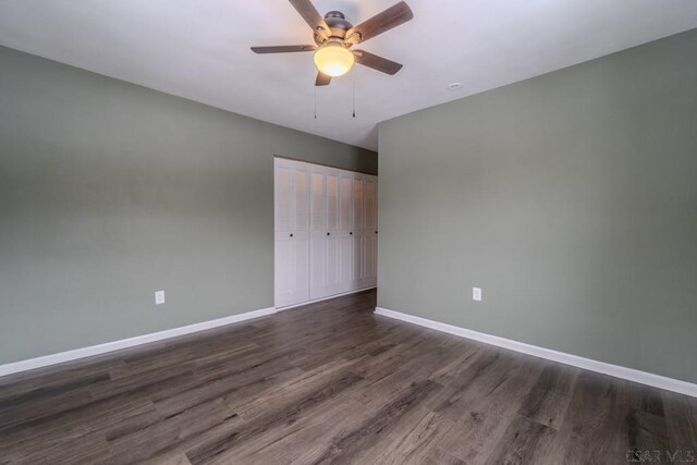 unfurnished bedroom featuring dark hardwood / wood-style flooring, ceiling fan, and a closet