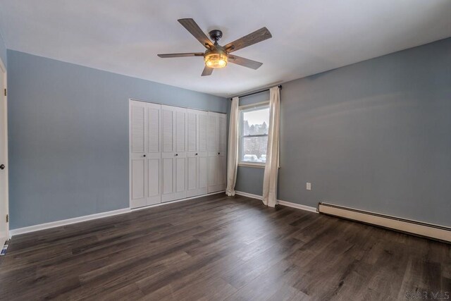 unfurnished bedroom with baseboard heating, ceiling fan, dark hardwood / wood-style floors, and a closet