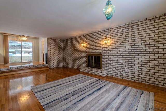 unfurnished living room with brick wall, a fireplace, and wood-type flooring