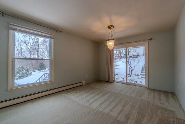 unfurnished dining area with light carpet, a baseboard heating unit, and a wealth of natural light