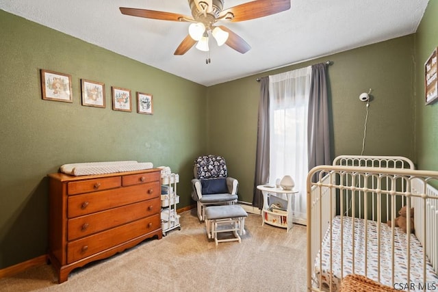 bedroom with a crib, ceiling fan, and carpet flooring