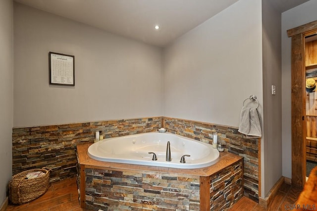 bathroom with tiled bath and hardwood / wood-style floors