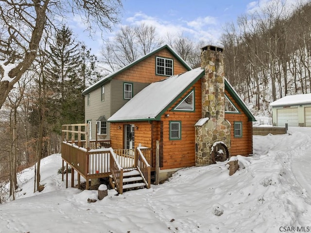 snow covered rear of property with a wooden deck and a garage