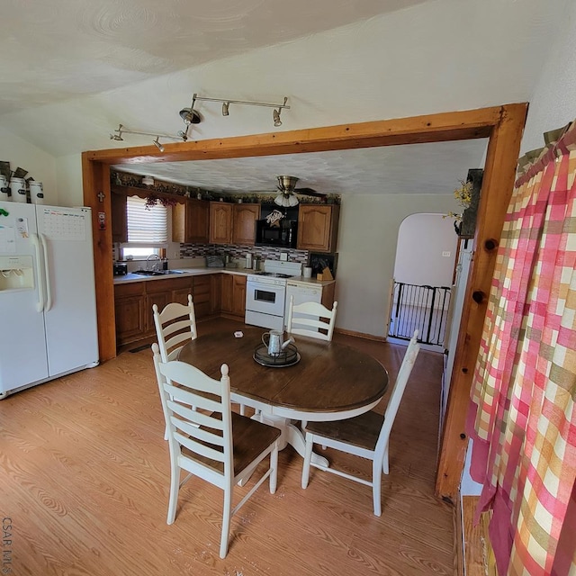 dining space with vaulted ceiling, sink, and light wood-type flooring