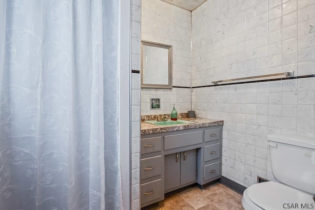 bathroom featuring tile walls, vanity, tile patterned flooring, and toilet