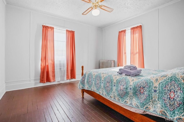 bedroom featuring multiple windows, radiator, dark hardwood / wood-style floors, and a textured ceiling