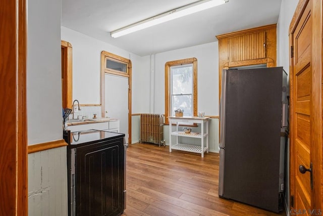 kitchen with radiator, stainless steel fridge, hardwood / wood-style floors, and sink