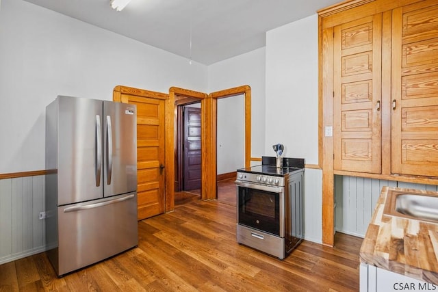 kitchen with stainless steel appliances, dark hardwood / wood-style floors, and butcher block countertops