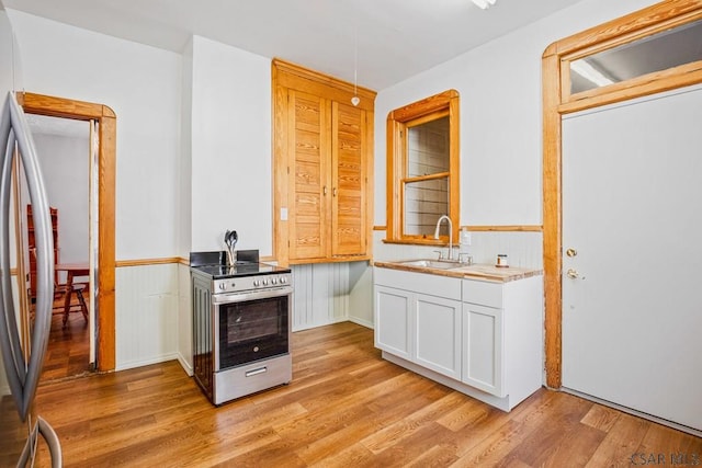 kitchen with white cabinetry, appliances with stainless steel finishes, sink, and light wood-type flooring